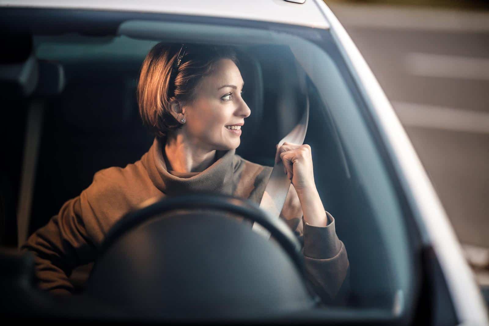 Sikker i trafikken. Kvindelig billist trager sikkerheedssele op.